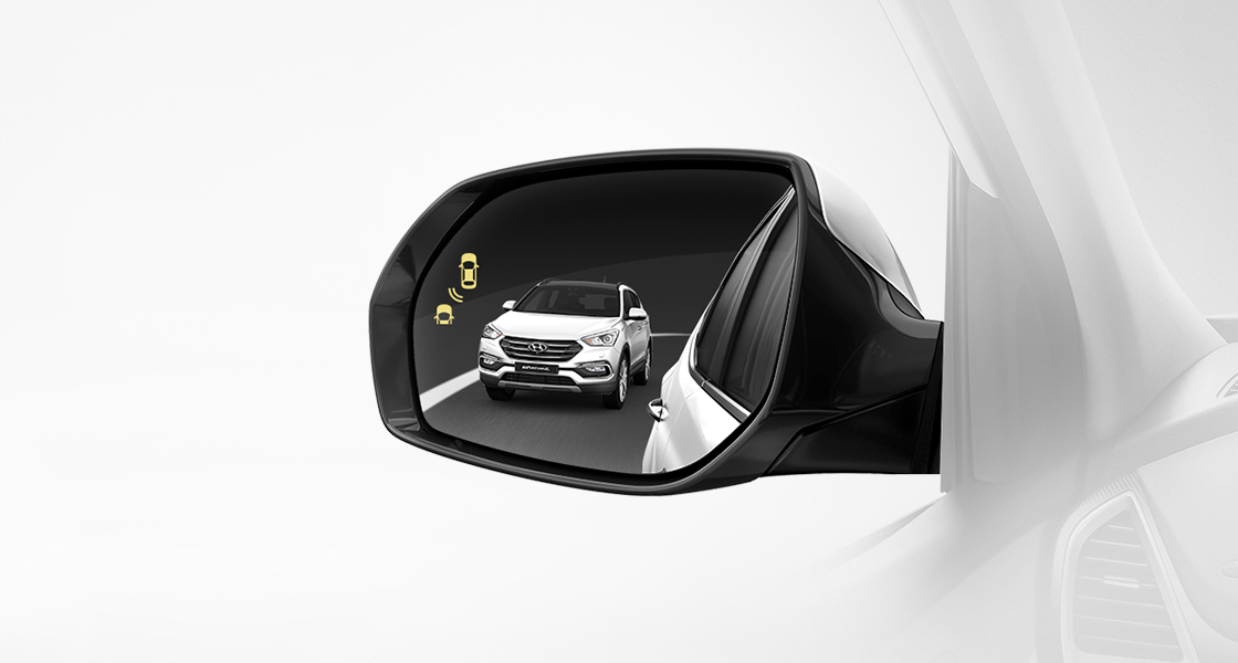 Blind spot detection activates on the side mirror with reflection of white Santa Fe approaching from behind